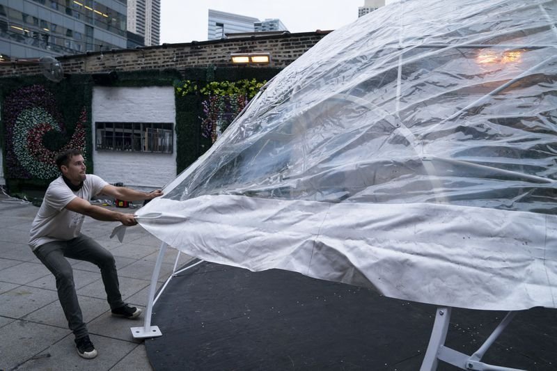 Matt Schroeder pulls the covering over the framework for a dome being installed Oct. 28, 2020, on the rooftop of the River North bar Joy District (E. Jason Wambsgans / Chicago Tribune)